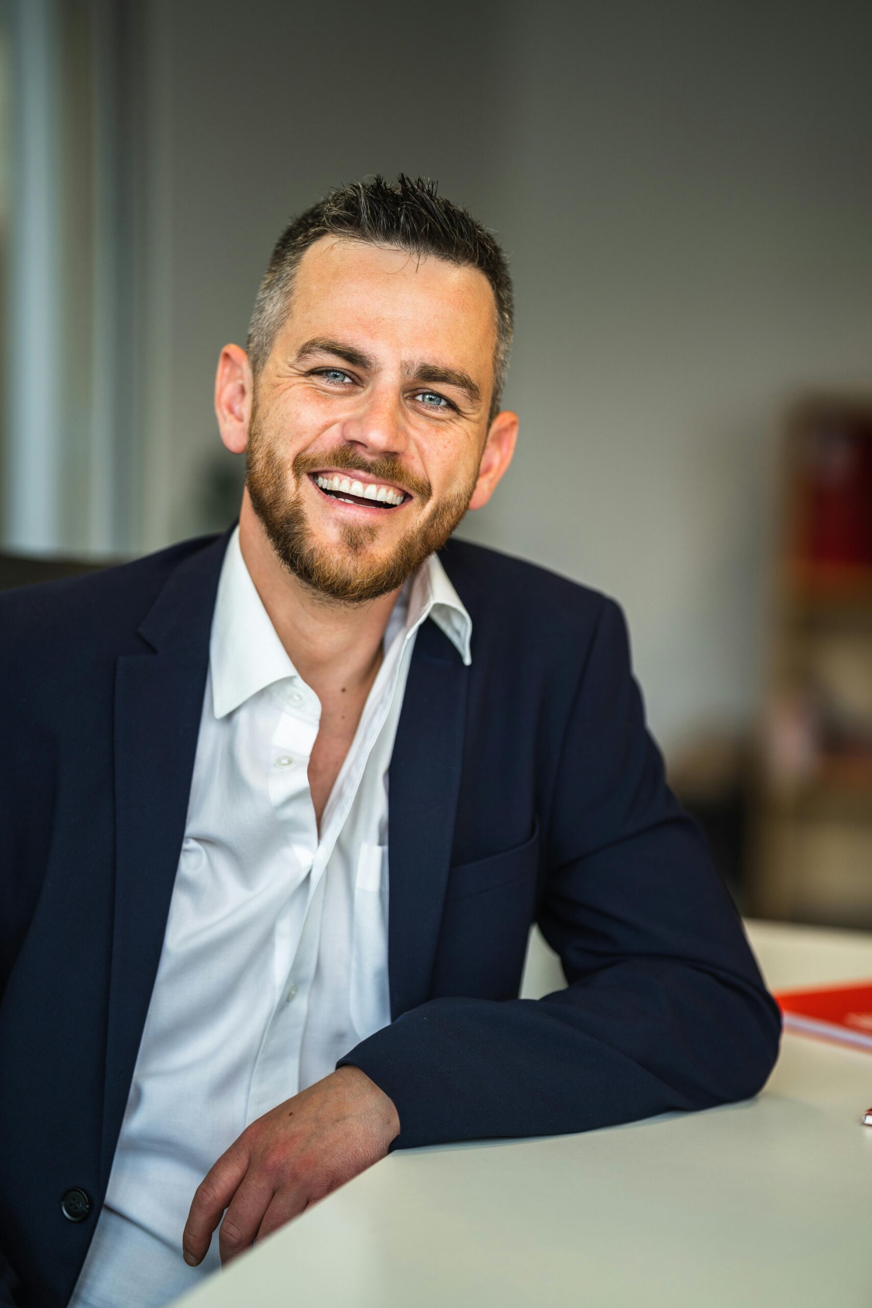 Business professional in suit smiling confidently in a modern office environment.